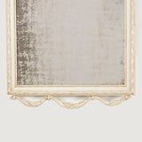 A small late 19th century mirror in a Louis XVI style with swag and bow crest and a later painted finish.