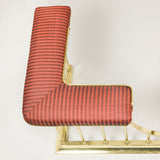An early 20th century brass club fender, the seat recovered in striped horsehair fabric.