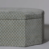 A rectangular ottoman stool with canted corners upholstered in a grey/blue gauffraged velvet, with hinged lid, the interior contrast lined in grey ticking.