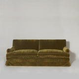 A large traditionally upholstered sofa covered in an olive-green mohair velvet, piped with green linen.