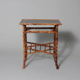 An early 20th century rectangular bamboo table with a lacquer panel top decorated with birds and foliage.