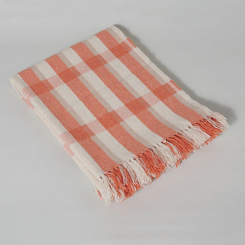 The Sutherland lap rug woven in Scotland from 100% merino lambswool in a shadow plaid design with a hand knotted fringe. Coral.