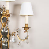 A pair of gilt iron and crystal two-branch wall lights by Maison Bagues. Mid 20th century.