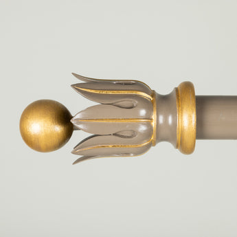 Carved wooden curtain pole finials in the form of a ball and stylised acanthus leaves.