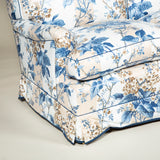A large three seat sofa in a traditional style upholstered in a floral chintz fabric in blues and browns on a white ground.
