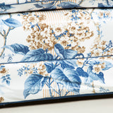 A large three seat sofa in a traditional style upholstered in a floral chintz fabric in blues and browns on a white ground.