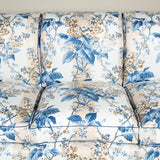 A large three seat sofa in a traditional style upholstered in a floral chintz fabric in blues and browns on a white ground.