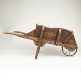 A brown painted Edwardian childs wheelbarrow with simple geometric decoration.