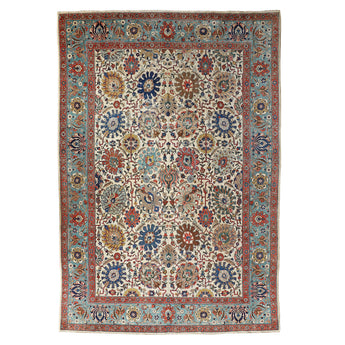 AN ANTIQUE TABRIZ CARPET, THE TURQUOISE BORDER AND WHITE GROUND WITH AN ALL-OVER FLORAL DESIGN IN GOLDS, REDS, PALE BLUES AND INDIGO. EARLY 20TH CENTURY.