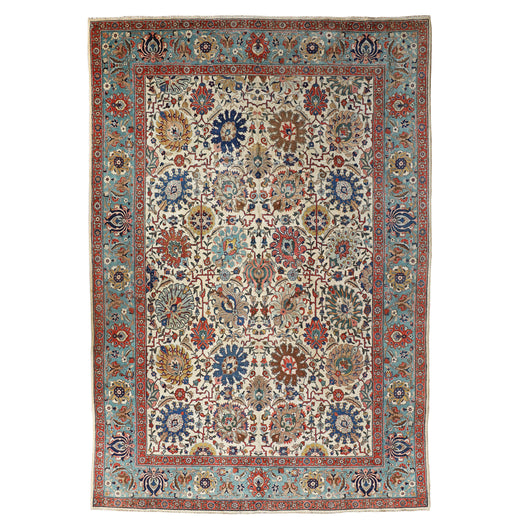 AN ANTIQUE TABRIZ CARPET, THE TURQUOISE BORDER AND WHITE GROUND WITH AN ALL-OVER FLORAL DESIGN IN GOLDS, REDS, PALE BLUES AND INDIGO. EARLY 20TH CENTURY.