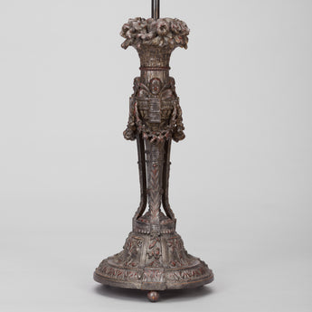 AN ELABORATELY CARVED LAMP BASE WITH A PAINTED BRONZE FINISH, PROBABLY LATE 19TH CENTURY, REWIRED.
