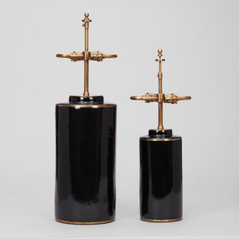 A PAIR OF SMALL BLACK POTTERY CYLINDER VASES AND A SINGLE LARGER VERSION,  WITH BRASS BANDS TO THE RIMS,  WIRED AS LAMPS.