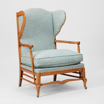 A COTSWOLD STYLE PALE OAK WING ARMCHAIR WITH A SERPENTINE BACK AND TURNED-OUT ARMRESTS. CIRCA 1930.