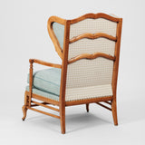 A COTSWOLD STYLE PALE OAK WING ARMCHAIR WITH A SERPENTINE BACK AND TURNED-OUT ARMRESTS. CIRCA 1930.