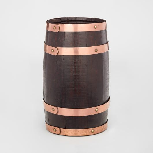 AN EARLY 20TH CENTURY COOPERED DARK OAK BARREL WITH COPPER BANDING.