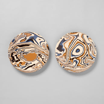 TWO ROUND MARBELISED PLATES WITH BLUE AND OCHRE DECORATION ON A CREAM GROUND.