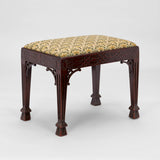 AN EDWARDIAN STOOL WITH A FRETWORK DECORATED FRAME, TAPERING LEGS AND A NEEDLEPOINT PANEL TO THE TOP.