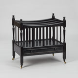 A MID-20TH CENTURY CANTERBURY WITH FOUR SECTIONS AND A SLIM DRAWER TO THE BASE, WITH A LATER EBONSIED FINISH.