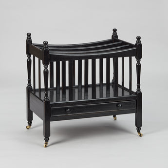A MID-20TH CENTURY CANTERBURY WITH FOUR SECTIONS AND A SLIM DRAWER TO THE BASE, WITH A LATER EBONSIED FINISH.