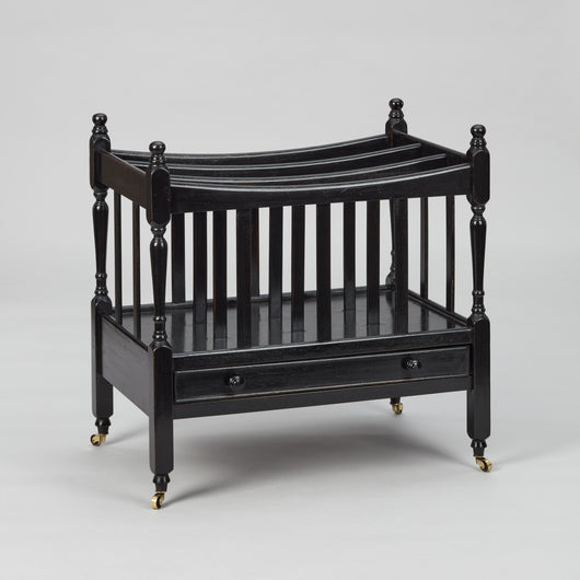 A MID-20TH CENTURY CANTERBURY WITH FOUR SECTIONS AND A SLIM DRAWER TO THE BASE, WITH A LATER EBONSIED FINISH.