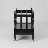 A MID-20TH CENTURY CANTERBURY WITH FOUR SECTIONS AND A SLIM DRAWER TO THE BASE, WITH A LATER EBONSIED FINISH.