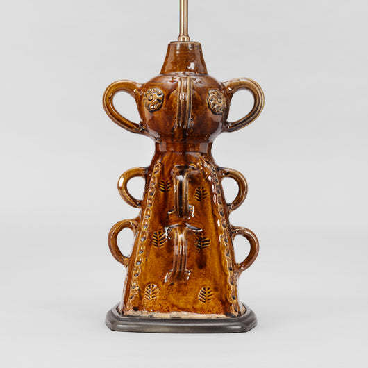 A FRENCH BROWN GLAZED POTTERY PYRAMIDAL-SHAPED STAND WITH LOOP HANDLES AND INCISED DECORATION WIRED AS A LAMP.