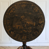 A 19TH CENTURY CHINESE EXPORT CENTRE TABLE WITH A LACQUERED AND DECORATED TILT TOP ON A CARVED AND GILDED BASE.