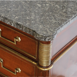 A 19TH CENTURY THREE-DRAWER MAHOGANY COMMODE IN THE LOUIS XVI TASTE, WITH A GREY MARBLE TOP AND BRASS MOUNTS.
