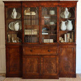 AN EARLY 19TH CENTURY ENGLISH REGENCY MAHOGANY BREAKFRONT SECRETAIRE BOOKCASE, WITH ASTRAGAL GLAZED DOORS AND WRITING FALL.