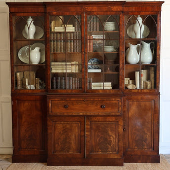 AN EARLY 19TH CENTURY ENGLISH REGENCY MAHOGANY BREAKFRONT SECRETAIRE BOOKCASE, WITH ASTRAGAL GLAZED DOORS AND WRITING FALL.