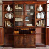 AN EARLY 19TH CENTURY ENGLISH REGENCY MAHOGANY BREAKFRONT SECRETAIRE BOOKCASE, WITH ASTRAGAL GLAZED DOORS AND WRITING FALL.