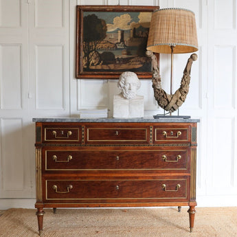 A FINE LOUIS XVI PERIOD MAHOGANY COMMODE WITH BRASS MOUNTS, INSET BRASS REEDED PILATERS AND EBONY AND BRASS CORNER PANELS, WITH A GREY MARBLE TOP.