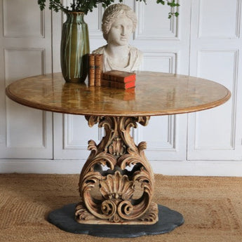 A MID 20TH CENTURY ITALIAN CENTRE TABLE WITH A PIETRA DURA TOP AND A CARVED AND GILDED BASE SET ON A MARBLE BASE.
