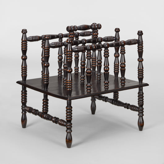 AN EARLY 20TH C. CANTERBURY WITH BOBBIN TURNED FRAME AND CARRYING HANDLE AND A PANEL BASE, EBONISED