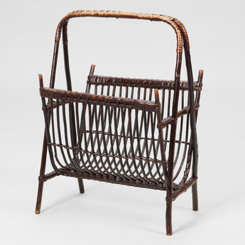 A BAMBOO AND RATTAN MAGAZINE STAND WITH A-FRAME SUPPORTS AND CARRYING HANDLE.