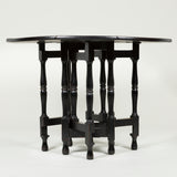 An ebonised early 20th century round oak table with 8 segmental drop-leaves on a four gate-leg base.