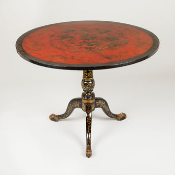 A Chinese export round table with a red lacquer top & black & gilt tripod base with claw feet. Late 18th century.