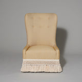 A bespoke made Friar’s chair in a cream stripe fabric, the base finished with a woven fringe..
