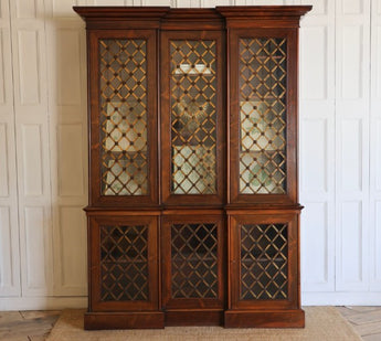 A VERY ELEGANT, 19TH CENTURY ENGLISH WILLIAM IV PERIOD INVERTED BREAKFRONT BOOKCASE IN ROSEWOOD, THE GLAZED DOORS WITH LATTICE AND ROSETTE BRASS GRILLS.