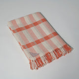 The Sutherland lap rug woven in Scotland from 100% merino lambswool in a shadow plaid design with a hand knotted fringe. Coral.