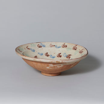 A modern French glazed pottery bowl decorated with brown and blue flashes on a cream ground.