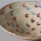 A modern French glazed pottery bowl decorated with brown and blue flashes on a cream ground.