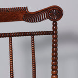 A mid-19th century open armchair with high bobbin turned spindle back and carved toprail and rosewood graining.