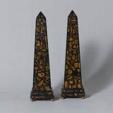 A pair of decoupage decorated wooden obelisks with stepped bases on brass ball feet. Probably 19th century or later.