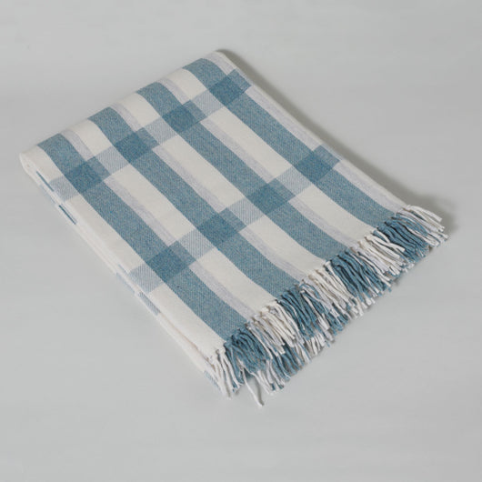 The Sutherland lap rug woven in Scotland from 100% merino lambswool in a shadow plaid design with a hand knotted fringe. Aqua.