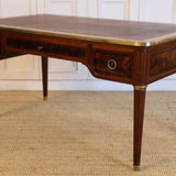 AN EARLY 20TH CENTURY FRENCH MAHOGANY DESK WITH REEDED LEGS, FLAME MAHOGANY VENEERED PANELS, BRASS MOUNTS AND ORIGINAL LEATHER TOP.