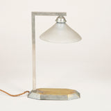 A small 1930’s chromed brass desk lamp with an octagonal base and glass shade.