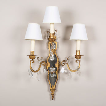 A pair of gilt iron and crystal two-branch wall lights by Maison Bagues. Mid 20th century.