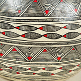 A pot-bellied papier mache pot with red and black geometric decoration on a white ground. Wired as a lamp.