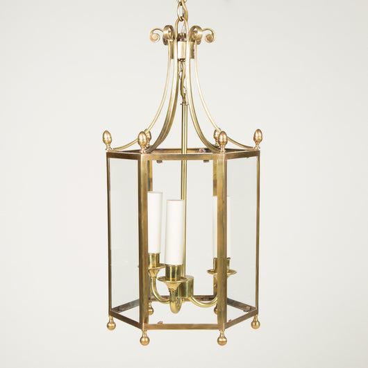 A Colefax and Fowler gilt brass hexagonal hanging lantern with scroll decorated top and finials. Late 20th century. Rewired.